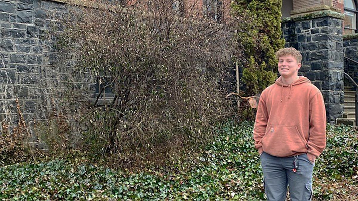 Photo of man wearing orange hoodie in front of building